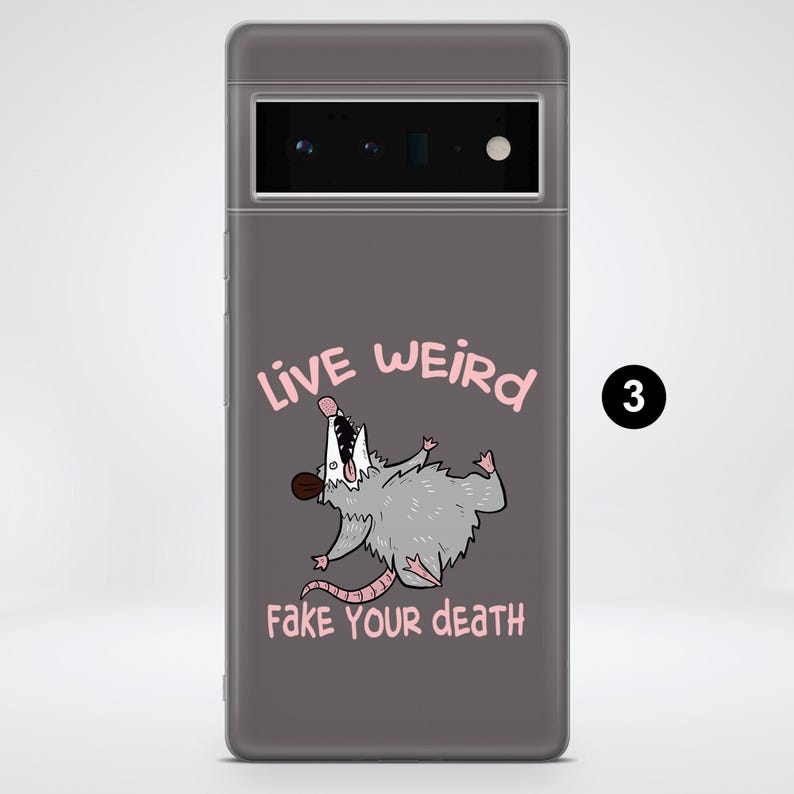 Puede incluir: Una funda de tel&eacute;fono gris con un opossum de dibujos animados y el texto "Live Weird Fake Your Death".