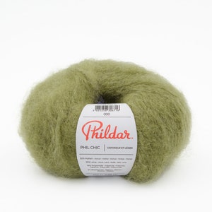 May include: A skein of green yarn labeled "Phil Chic" by Phildar. The label lists the yarn composition as 50% mohair, 32% wool, 10% polyamide, and 2% elastane.