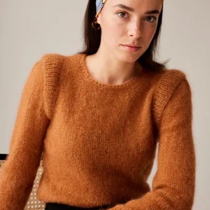 May include: A brown fuzzy sweater with puffed shoulders. The sweater is made of a soft, comfortable material.