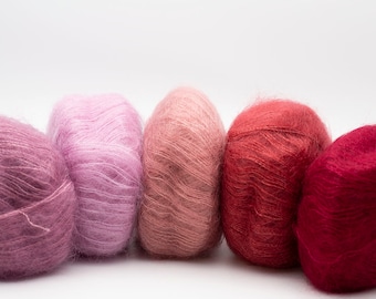 May include: Five balls of yarn in shades of pink, red, and burgundy. The yarn is soft and fluffy, and the colors are arranged in a gradient from light to dark.