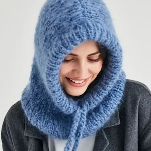 May include: A blue knitted hooded scarf with a long tie. The scarf is made of a soft, fuzzy yarn.