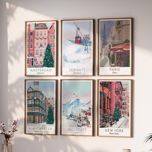 May include: Six framed art prints showcasing cityscapes of Amsterdam, Zermatt, Paris, Manchester, Hallstatt, and New York. Each print has a wooden frame and shows a winter scene with city names.