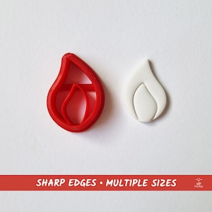 Puede incluir: Cortador de galletas de plástico rojo en forma de llama con un recorte de fondant blanco de la misma forma.