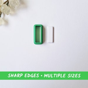 Könnte beinhalten: Ein grünes Plastikrechteck mit einem kleineren Rechteck, das aus der Mitte ausgeschnitten ist. Daneben befindet sich ein weißes Rechteck. Der Text "SHARP EDGES • MULTIPLE SIZES" ist auf einem grünen Banner unter den Rechtecken gedruckt.