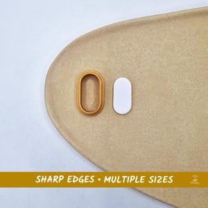May include: A gold oval cookie cutter and a white oval-shaped object are shown on a tan surface. The text "SHARP EDGES • MULTIPLE SIZES" is at the bottom of the image.