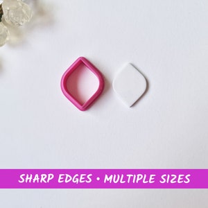 May include: Two diamond-shaped cookie cutters, one pink and one white. The pink cutter is slightly larger than the white cutter.