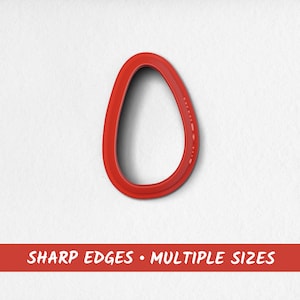 May include: Red plastic cookie cutter shaped like an egg.  The cutter has sharp edges and a smooth, rounded surface.
