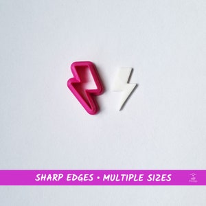 Può includere: Due stampini per biscotti a forma di fulmine, uno rosa e uno bianco. Il testo "SHARP EDGES - MULTIPLE SIZES" è stampato su uno striscione rosa sotto gli stampini.