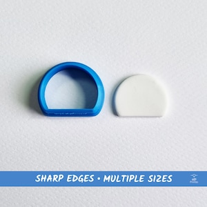 Puede incluir: Un cortador de galletas de plástico azul con forma de semicírculo, junto a un semicírculo blanco de arcilla polimérica. El texto "SHARP EDGES • MULTIPLE SIZES" está impreso en una pancarta azul debajo de la imagen.