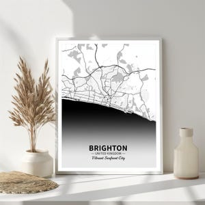 May include: A framed monochrome map print of Brighton, UK. The detailed map shows roads and buildings, with a gradient effect at the bottom. Text reads "BRIGHTON - UNITED KINGDOM - Vibrant Seafront City".
