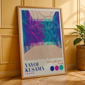 May include: A framed art print featuring a colorful abstract design with blue, purple, and teal hues. The print includes the text "YAYOI KUSAMA TOKYO" and Japanese characters. The artwork is displayed in a light brown wooden frame.
