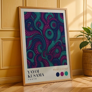 Puede incluir: Un cuadro enmarcado con un diseño abstracto de patrones arremolinados en verde azulado, morado y azul marino. La impresión incluye el texto "YAYOI KUSAMA TOKYO" y texto japonés. La obra de arte se muestra en un marco de madera.