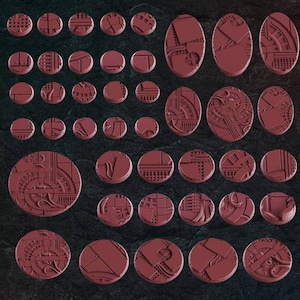 Könnte beinhalten: Ein Set mit 30 runden und ovalen Plastiksockeln für Miniaturen. Die Sockel sind in einem tiefen Burgunderrot gehalten und weisen komplizierte, detaillierte Designs von Zahnrädern, Rohren und anderen industriellen Elementen auf.