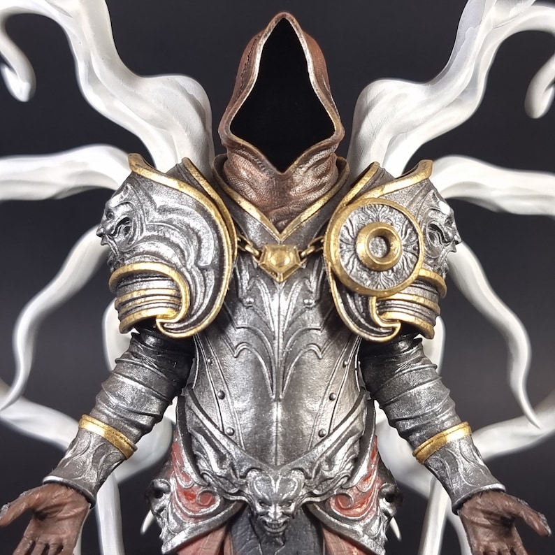 Peut inclure: Une figurine d&eacute;taill&eacute;e d'une figure capuchonn&eacute;e portant une armure argent&eacute;e et dor&eacute;e avec une aura blanche et fum&eacute;e. La figure a une capuche brun fonc&eacute; et une cuirasse argent&eacute;e avec des d&eacute;tails complexes.