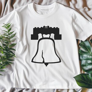 May include: White t-shirt featuring a black silhouette of the Liberty Bell and Independence Hall.