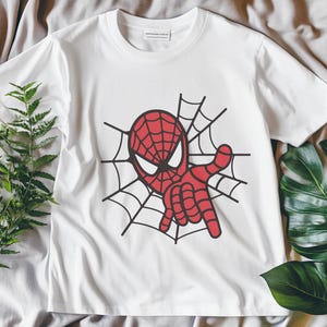 May include: White t-shirt with a red and black Spiderman graphic on a white web design.