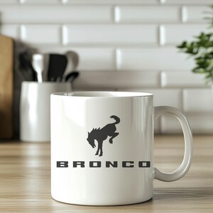 May include: White ceramic mug with a black silhouette of a horse and the word "BRONCO" printed on it.