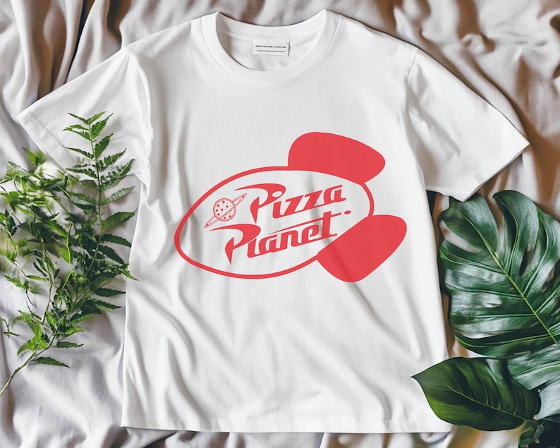 May include: White t-shirt with a red Pizza Planet logo. The logo features a stylized planet with a ring and the words "Pizza Planet" in a retro font. The shirt is made of a soft material and has short sleeves.