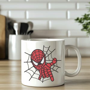 May include: White ceramic mug with a red and black cartoon image of Spiderman in a web. The mug has a handle.
