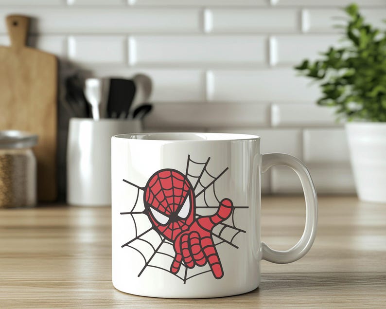 May include: White ceramic mug with a red and black cartoon image of Spiderman in a web. The mug has a handle.