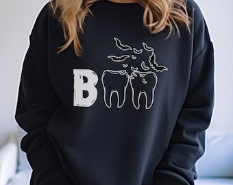 May include: Black sweatshirt with a white graphic of two teeth with bats flying around them and the word "BOO" printed on the front.