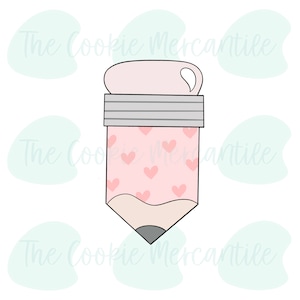 May include: A pencil-shaped cookie cutter with a pink body covered in small hearts. The eraser is light pink, and the metal band is silver. The pencil tip is gray. The text "The Cookie Mercantile" is in the background.