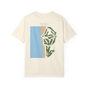 May include: Cream-colored t-shirt featuring a graphic design. The design includes a blue rectangle, a tan shape, and a green abstract shape. The text "Sheep Ranch" and "Bandon, OR" is printed above the graphic.