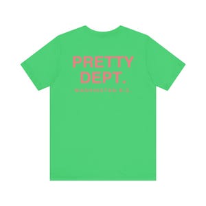May include: A bright green t-shirt with the text "PRETTY DEPT." in pink, with "WASHINGTON D.C." below. The shirt is a solid color and has a crew neck.