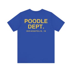 May include: A royal blue t-shirt with the words "POODLE DEPT." in yellow block letters. Below the text is "INDIANAPOLIS, IN" in yellow. The shirt is a solid color and has short sleeves.