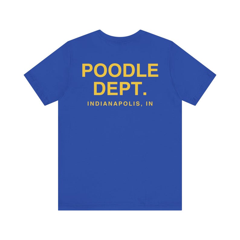 May include: A royal blue t-shirt with the words "POODLE DEPT." in yellow block letters. Below the text is "INDIANAPOLIS, IN" in yellow. The shirt is a solid color and has short sleeves.