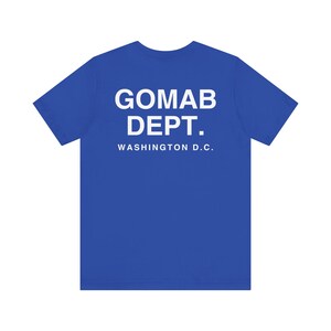 May include: A royal blue t-shirt with the text "GOMAB DEPT. WASHINGTON D.C." printed in white. The shirt is a crew neck style and appears to be made of a soft, comfortable material.