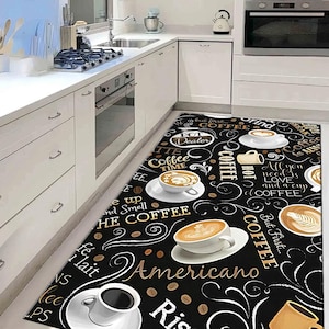 以下が含まれることがあります： コーヒーをテーマにした黒い長方形のキッチンラグ。コーヒーカップ、コーヒー豆、そして「Americano」、「Rise & Grind」、「But First... Coffee」などのテキストが特徴です。黒い背景に白と金のアクセント。