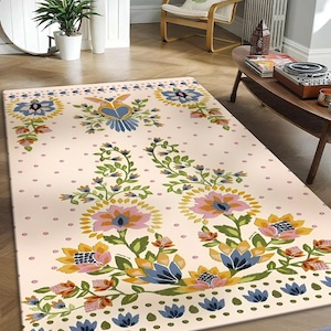 May include: A cream-colored rug with a floral pattern. The rug features pink, yellow, blue, and green flowers with a white background. The rug has a border of blue and green leaves.