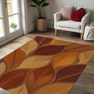 Peut inclure: Un tapis de sol brun, orange et rouge avec un motif de feuilles. Le tapis a un design contemporain avec un motif répétitif de feuilles stylisées.