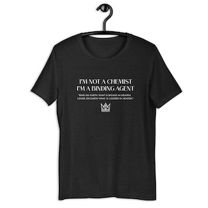 Könnte beinhalten: Ein schwarzes T-Shirt mit weißem Text, der lautet: "Ich bin kein Chemiker, ich bin ein Bindemittel." Der Text wird gefolgt von einem Zitat: "Binde auf Erden, was im Himmel gebunden ist, löse auf Erden, was im Himmel gelöst ist." Unter dem Zitat befindet sich eine Krone.