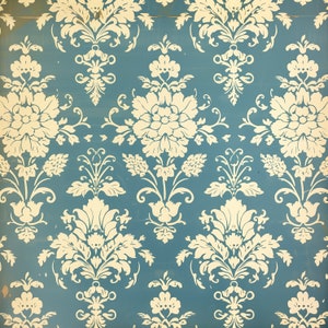 May include: A vintage wallpaper pattern with a repeating design of white floral motifs on a light blue background.