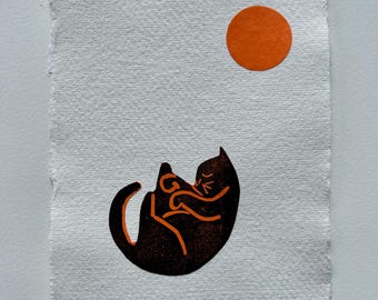 Colagem artesanal com impressão em relevo de um gato relaxando ao sol.