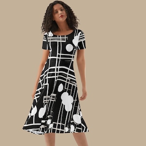 Pode incluir: Uma caneca de cerâmica branca com uma alça preta e o texto "But First, Coffee" em negrito preto. A caneca está sobre um fundo desfocado, sugerindo um ambiente acolhedor. A caneca parece ter capacidade para cerca de 350 ml.