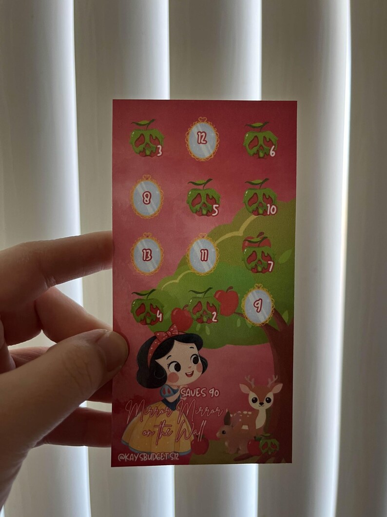 May include: A rectangular card featuring a Snow White theme. The card has a red background with illustrations of apples, mirrors, and a deer. Text on the card reads "Mirror Mirror on the Wall" and "Saves 90".
