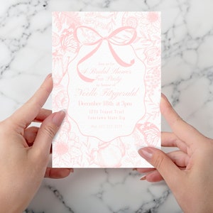 May include: A pink bridal shower tea party invitation with a floral design and a pink bow. The invitation includes the text "Join us for A Bridal Shower Tea Party in honour of Noelle Fitzgerald December 18th at 3pm 1234 Teapot Trail Yourteen State Zip".