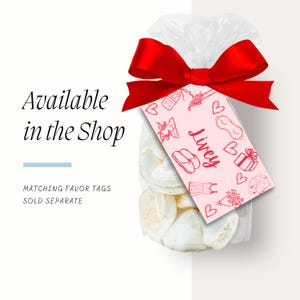 May include: A clear plastic bag filled with white meringue cookies tied with a red ribbon and a pink favor tag with the text "Livey" and pink illustrations of gifts, sleep masks, and other items.