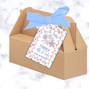 May include: A white gift tag with red and blue stars and fireworks. The tag says "Oh My Stars! Happy 4th of July" and "From: The Shepard's". The tag is tied with a blue ribbon to a brown cardboard gift box.