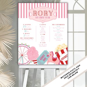 May include: A pink and white striped printable poster with a carnival theme. The poster says "RORY MY FIRST YEAR" and lists the child's stats, favorites, and what they can do. The poster features illustrations of a Ferris wheel, cotton candy, a carousel horse, and popcorn.