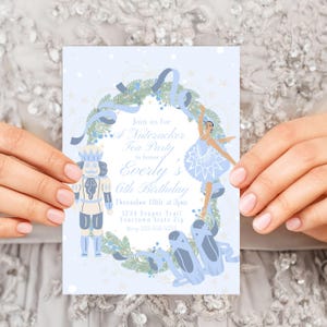 May include: A blue and white invitation for a Nutcracker Tea Party in honor of Everly's 6th birthday. The invitation features a ballerina and a Nutcracker doll in front of a wreath with blue ribbons. The text on the invitation reads "Join us for a Nutcracker Tea Party in honor of Everly's 6th Birthday, December 18th at 3pm, 1234 Teapot Trail, Yourtown State Zip."