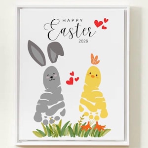 May include: A framed print with a white border featuring a whimsical Easter design. The artwork includes a gray bunny and a yellow chick, both created from footprints. The words "Happy Easter 2026" are written above the characters, with red heart accents.