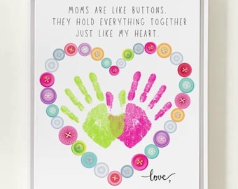 May include: A framed print with the text "MOMS ARE LIKE BUTTONS. THEY HOLD EVERYTHING TOGETHER JUST LIKE MY HEART." A heart shape is formed with colorful buttons, surrounding green and pink handprints. The word "love," is written in cursive.