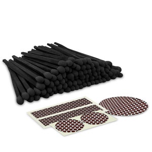 May include: A stack of 100 black matches with round black heads. The matches are arranged in a rectangular shape. There are three white stickers with brown honeycomb patterns.