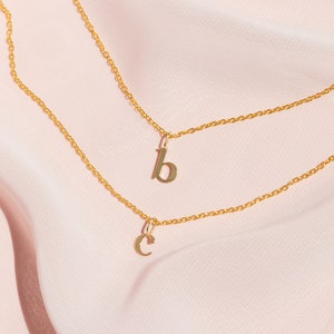 May include: Two gold necklaces with letter charms. The top necklace has a 'B' charm and the bottom necklace has a 'C' charm.