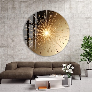May include: Circular wall art with a gold and yellow burst pattern, mounted on a concrete wall. The artwork is above a brown sofa, a white coffee table, and a potted plant. The design features radiating lines and a central bright light, creating a striking visual.