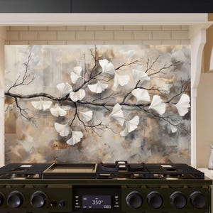 Puede incluir: Un protector de salpicaduras de cocina con un diseño pintado de una rama con hojas blancas de ginkgo sobre un fondo marrón y beige. El protector de salpicaduras está instalado sobre una estufa de gas negra con una pantalla digital que muestra "350°".